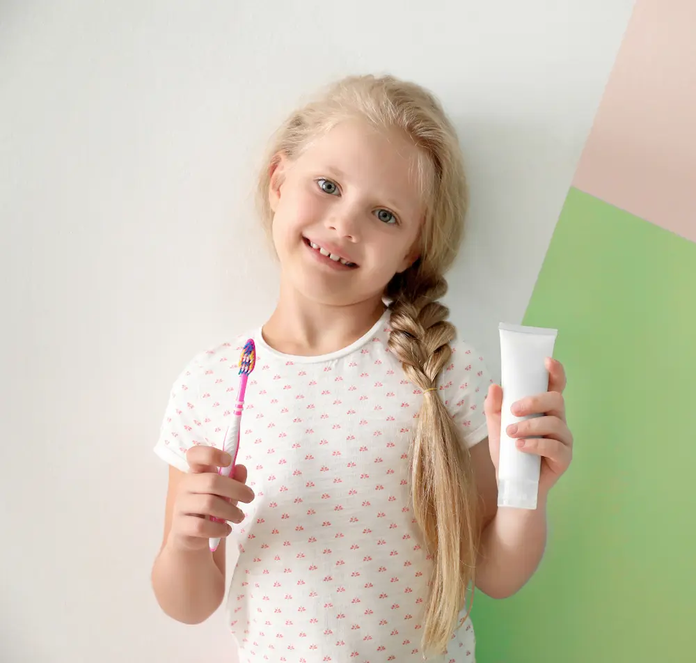 Girl holding toothbrush and kids toothpaste